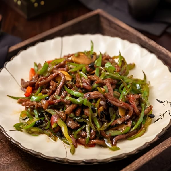 Bo Loong's stir-fried beef with green peppers and black beans on a decorative white plate.