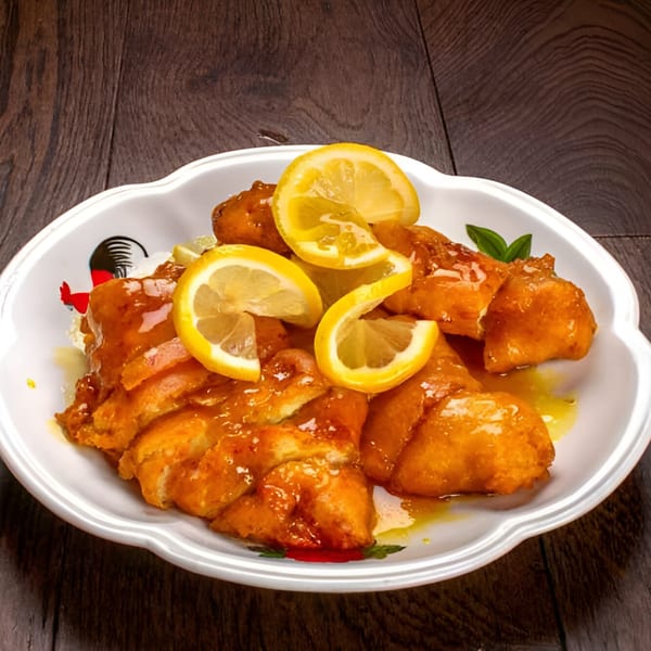 Bo Loong's lemon chicken, golden-fried and glazed, garnished with fresh lemon slices on a white plate.