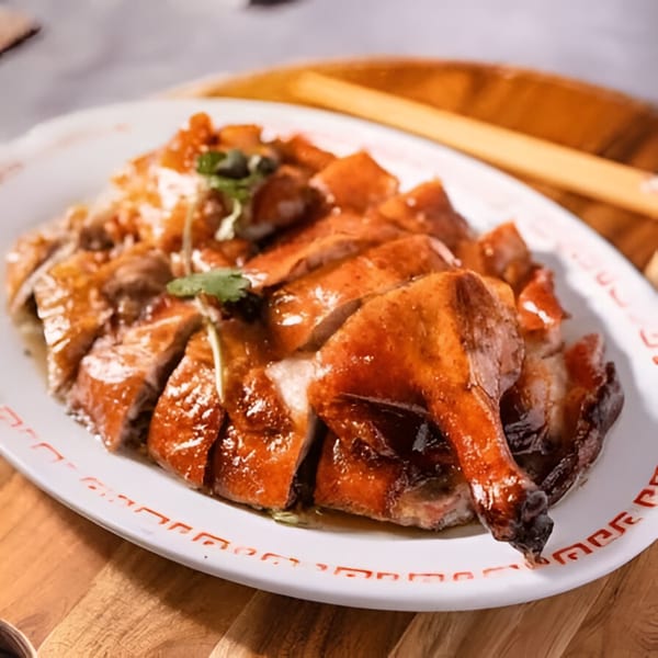 Bo Loong's roasted duck, glistening with sauce and garnished with cilantro, served on a white platter.