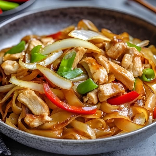 Close-up of Bo Loong's chicken chow fun with wide noodles, chicken, onions, and bell peppers.